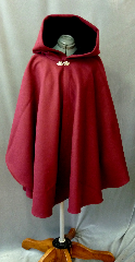 Cloak:2163, Cloak Style:Cape / Ruana, Cloak Color:Wine, Fiber / Weave:Heavy Wool Melton, Cloak Clasp:Vale, Hood Lining:Black Cotton Velveteen, Back Length:36", Neck Length:23", Seasons:Winter, Fall, Spring, Note:Luxurious and warm, this felted<br>wool melton ruana  is a deep cranberry color.<br>The full size hood is lined<br>in black  cotton velveteen and a<br>sturdy pewter Vale clasp closes the front.<br>A cross between a cape and a cloak,<br>a ruana is a great way to keep warm when<br>frequent, unhindered use of your arms is needed..
