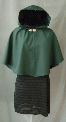 Cloak:2396, Cloak Style:Fuller Half Circle Child's, Cloak Color:Hunter Green, Fiber / Weave:Wool Gabardine, Cloak Clasp:Bavarian - Silvertone, Hood Lining:Unlined, Back Length:22", Neck Length:17", Seasons:Spring, Fall, Note:This short cloak is a fuller half circle.<br>The smaller neck makes this a good choice for a small child.<br>It is made from a deep green wool gabardine finished with a<br>silvertone Bavarian style hook and eye clasp.<br>Dry Clean or handwash cold, wrap in a towel and air dry..