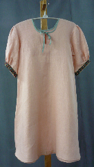Gown ID:G549, Gown Color:Peach, Style:Child Gown, Sleeve:Short w slight gather, Trim:Gold/Red Running Vine at bicep, Neckline Type:Keyhole with mint bias tape tie, Fabric:Linen, Sleeve Length:14.5", Back Length:30".